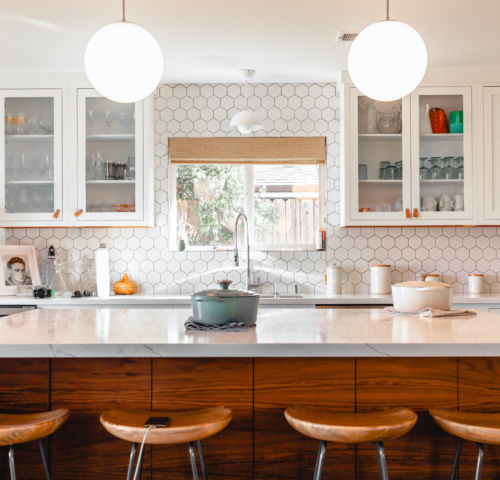 Bright White Kitchen With Island And White Hexagonal Tiling Aloing Wall With A Window Over The Sink