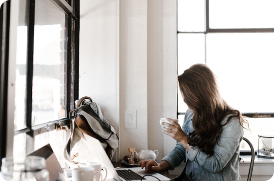 Woman At Desk With A Laptop Holding A Coffee Mug