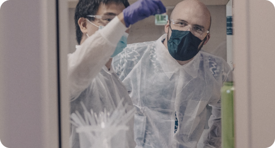 Two Scientists In Lab Covers Inspecting an Object